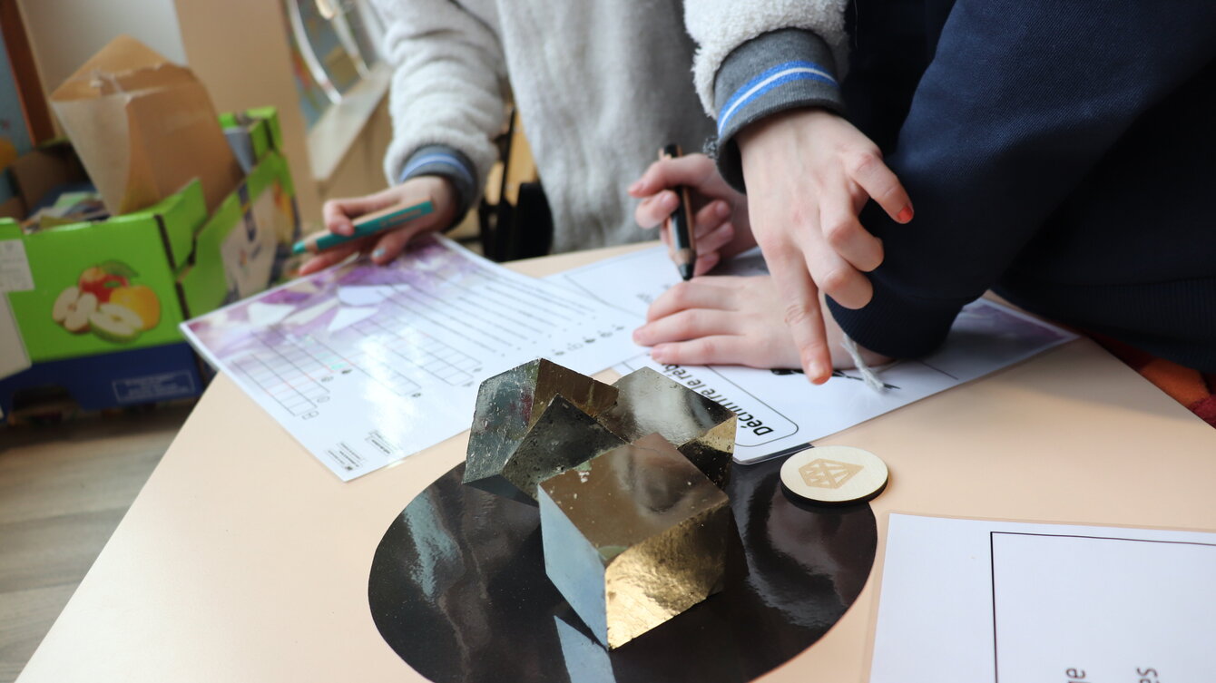 Minéraux sur une table, une main d'enfant les montre