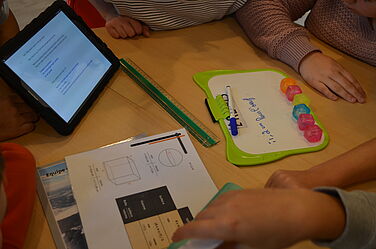 Des élèves travaillent autour d'une table avec une tablette tactile lors d'un atelier pédagogique