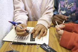 Mains des élèves qui travaillent sur l’atelier pédagogique, ils sont en train d'écrire