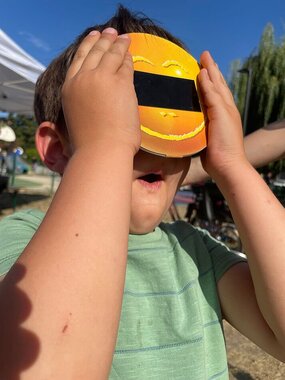 Enfant qui observe le Soleil à l'aide de lunettes dédiées